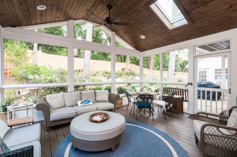 Screened in porch with furniture and a ceiling fan