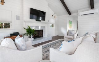 Cozy sunroom living space with fireplace, TV and white furniture