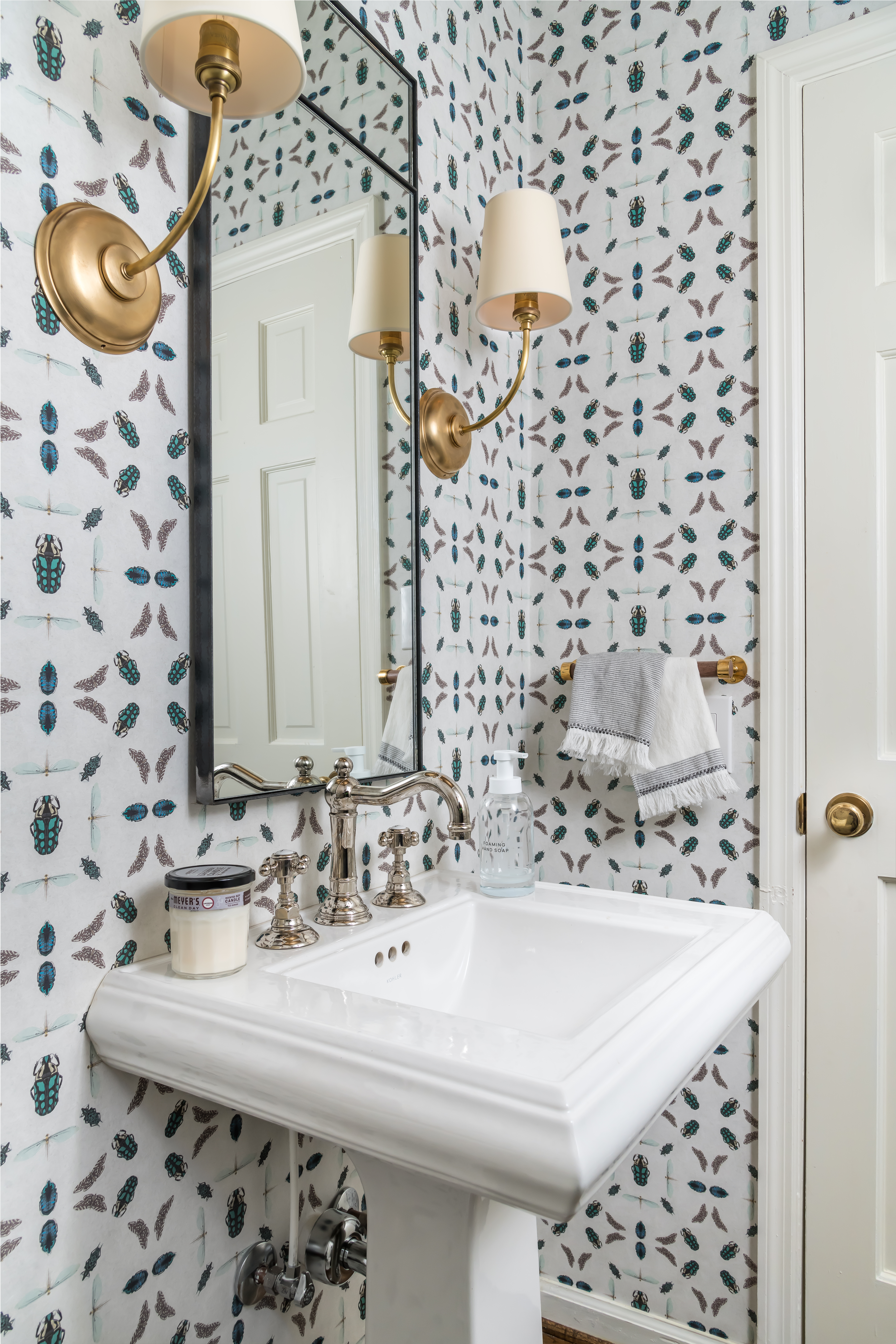 Stylish powder bath with patterned walls and gold hardware