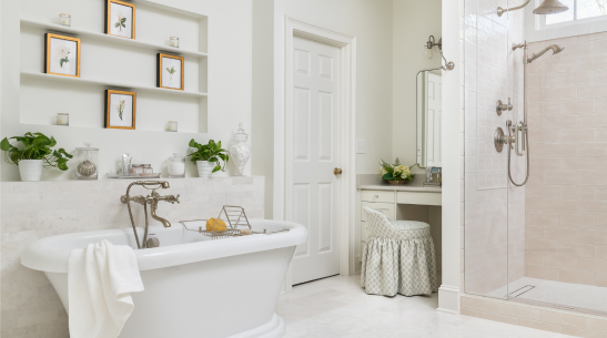 An all-white bathroom with a makeup vanity, a bathtub and a shower with silver fixtures.