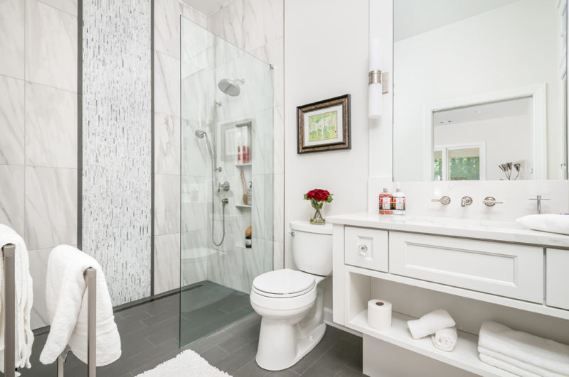 A sleek, modern bathroom with white fixtures and luxurious marble walls, creating a sophisticated ambiance.