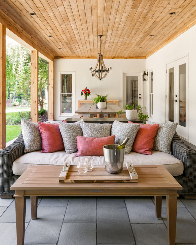 A cozy outdoor space with a couch, coffee table, and dining table under a covered patio.