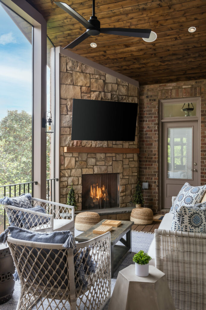 A cozy screened porch featuring a fireplace and a television, perfect for relaxing and enjoying the outdoors.