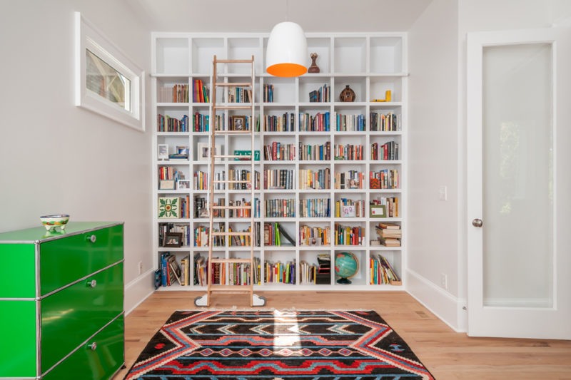 Green dresser and bookshelves in a well-decorated room, showcasing an aesthetically designed bookshelf with a rolling ladder.