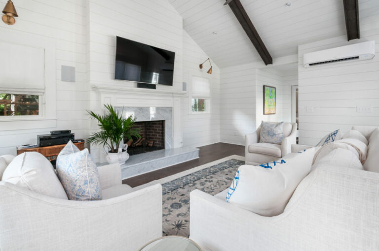 A tranquil white sunroom with a fireplace and TV, offering a comfortable living area.