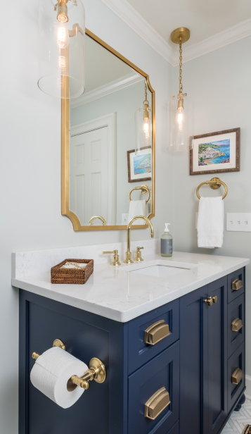 A bathroom featuring a navy blue vanity complemented by gold fixtures.
