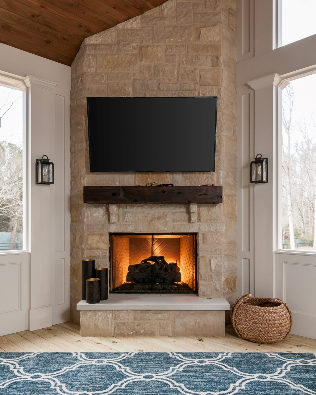 A TV mounted above a fireplace in a sunroom