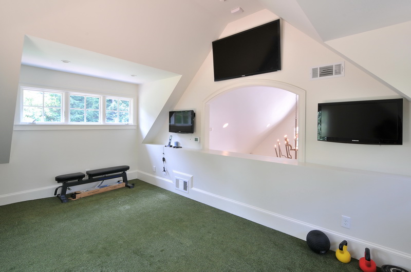 a room with 3 televisions and exercise equipment in it
