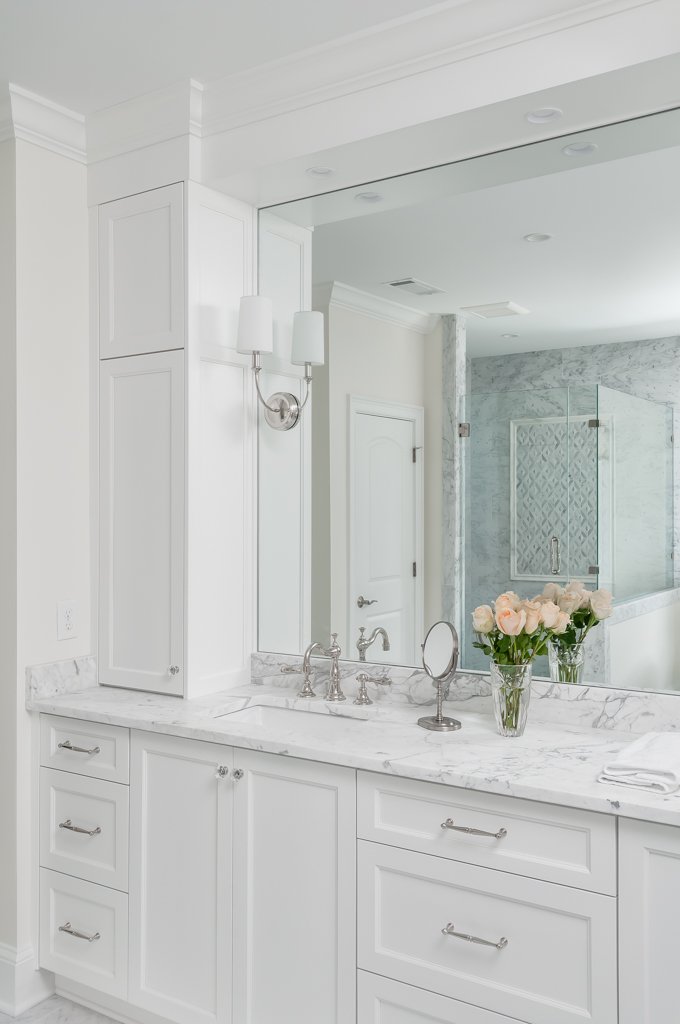 a bathroom with two sinks and a large mirror with bright white cabinets