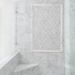 a walk-in shower with a built-in step, marble walls, and marble flooring