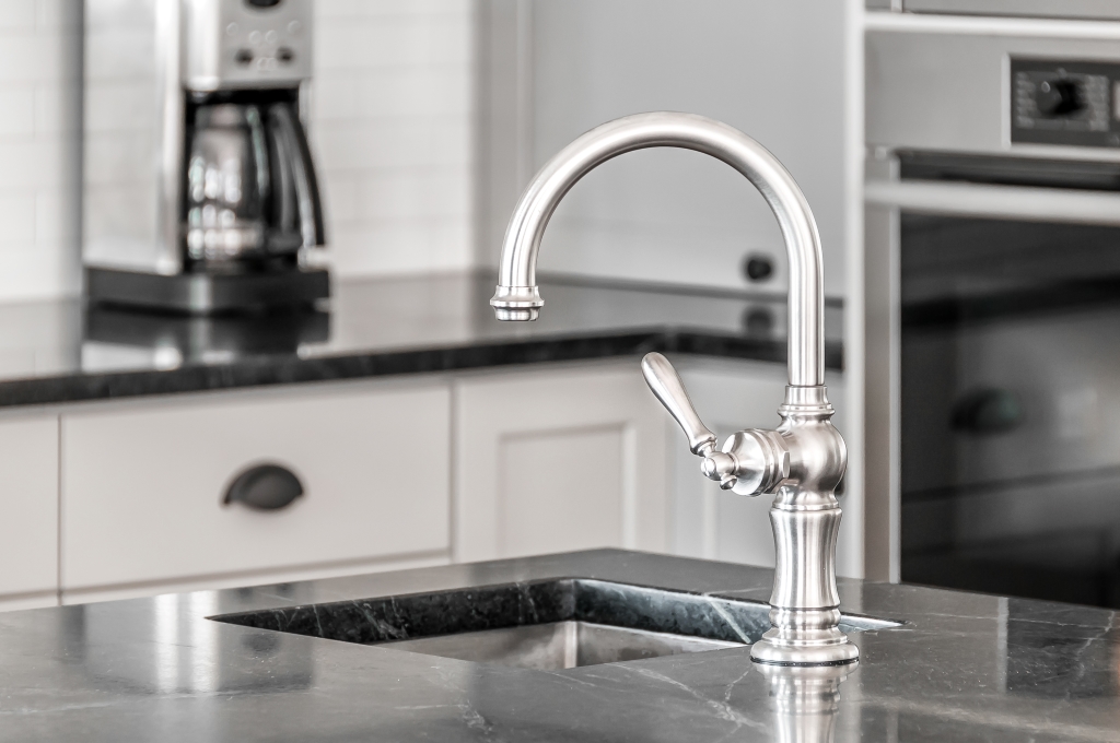 Closeup of stainless steel faucet on marble-topped kitchen island