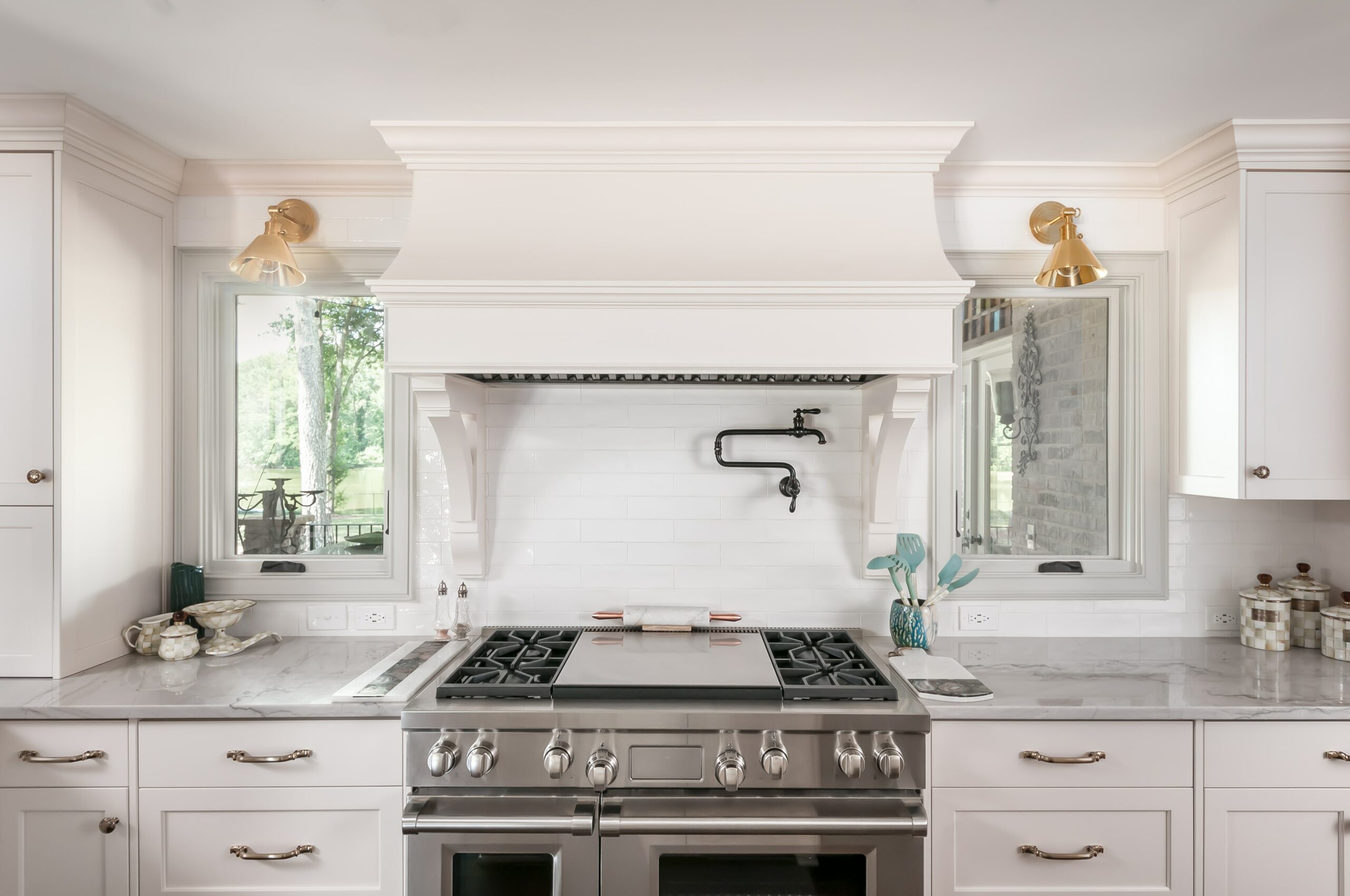 White kitchen with gold fixtures and stainless steel gas range stove