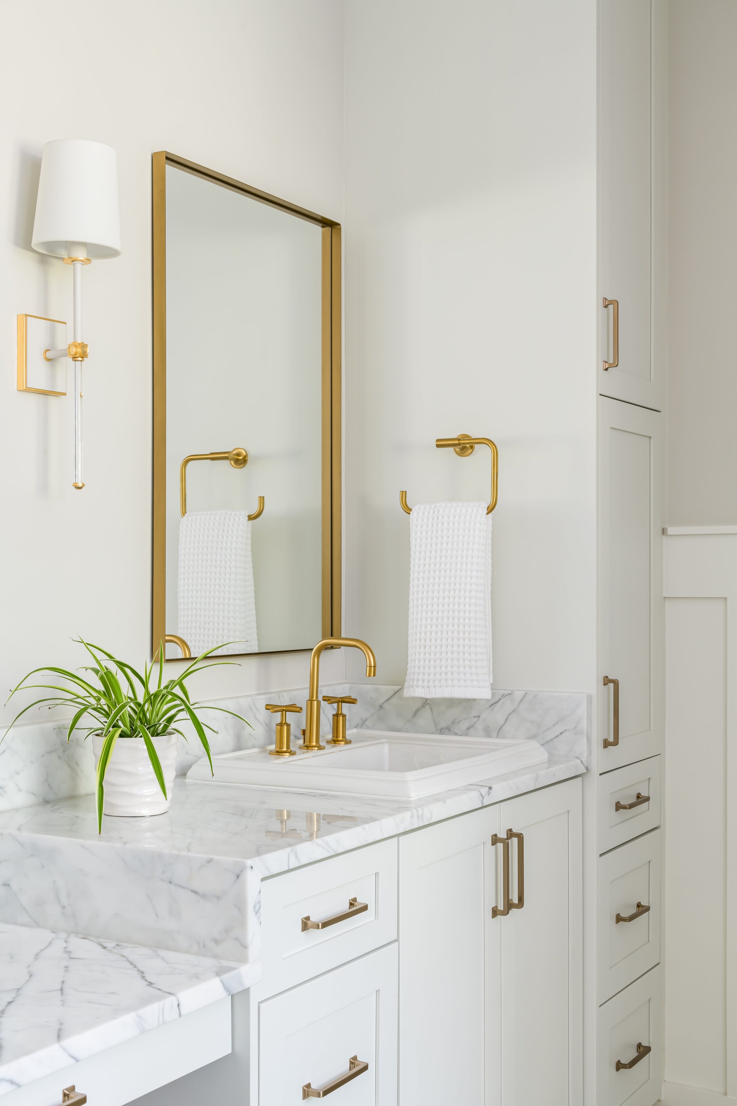 a newly remodeled bathroom with marble counter tops and gold faucets