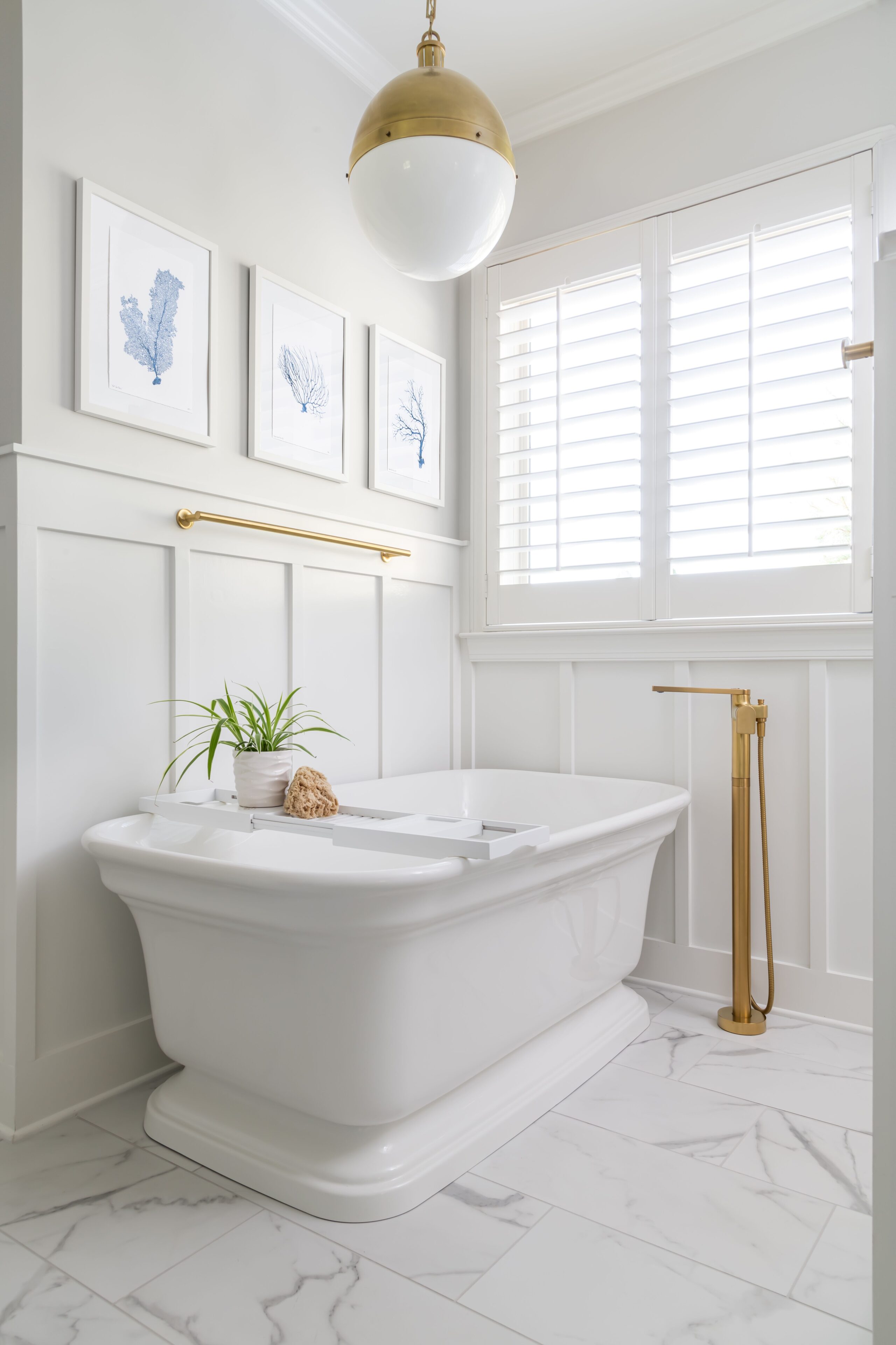 a white bath tub sitting under a window with decor items on the wall