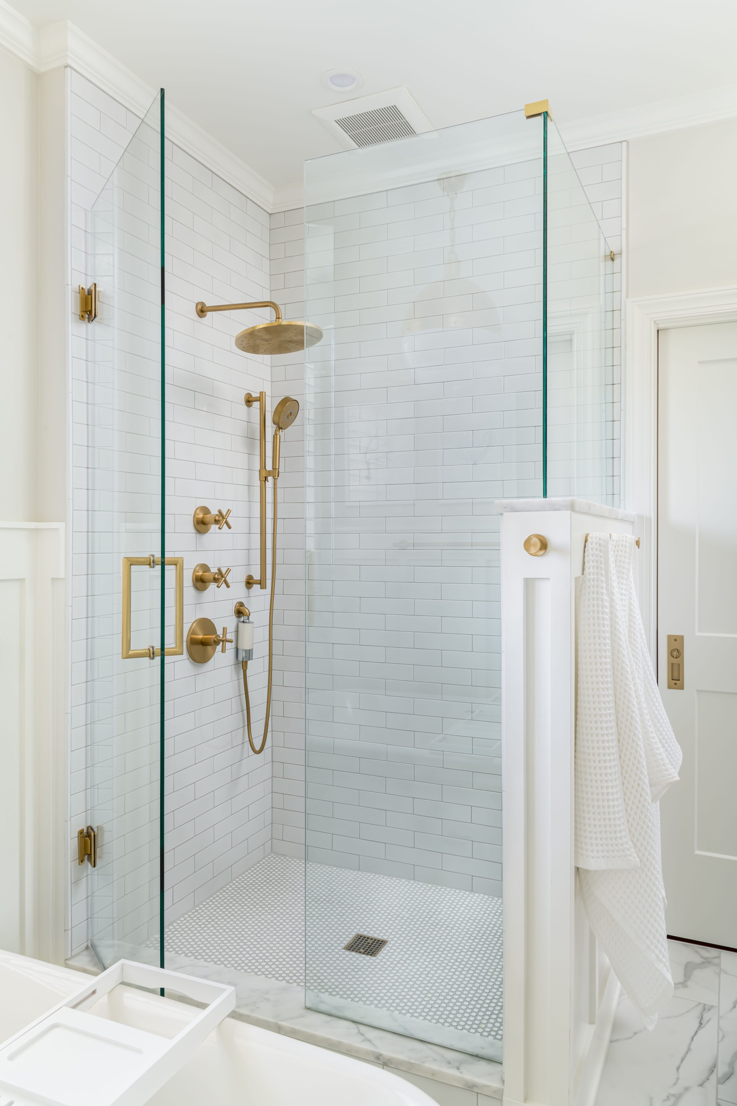 a newly remodeled bathroom with a walk in shower with gold accents