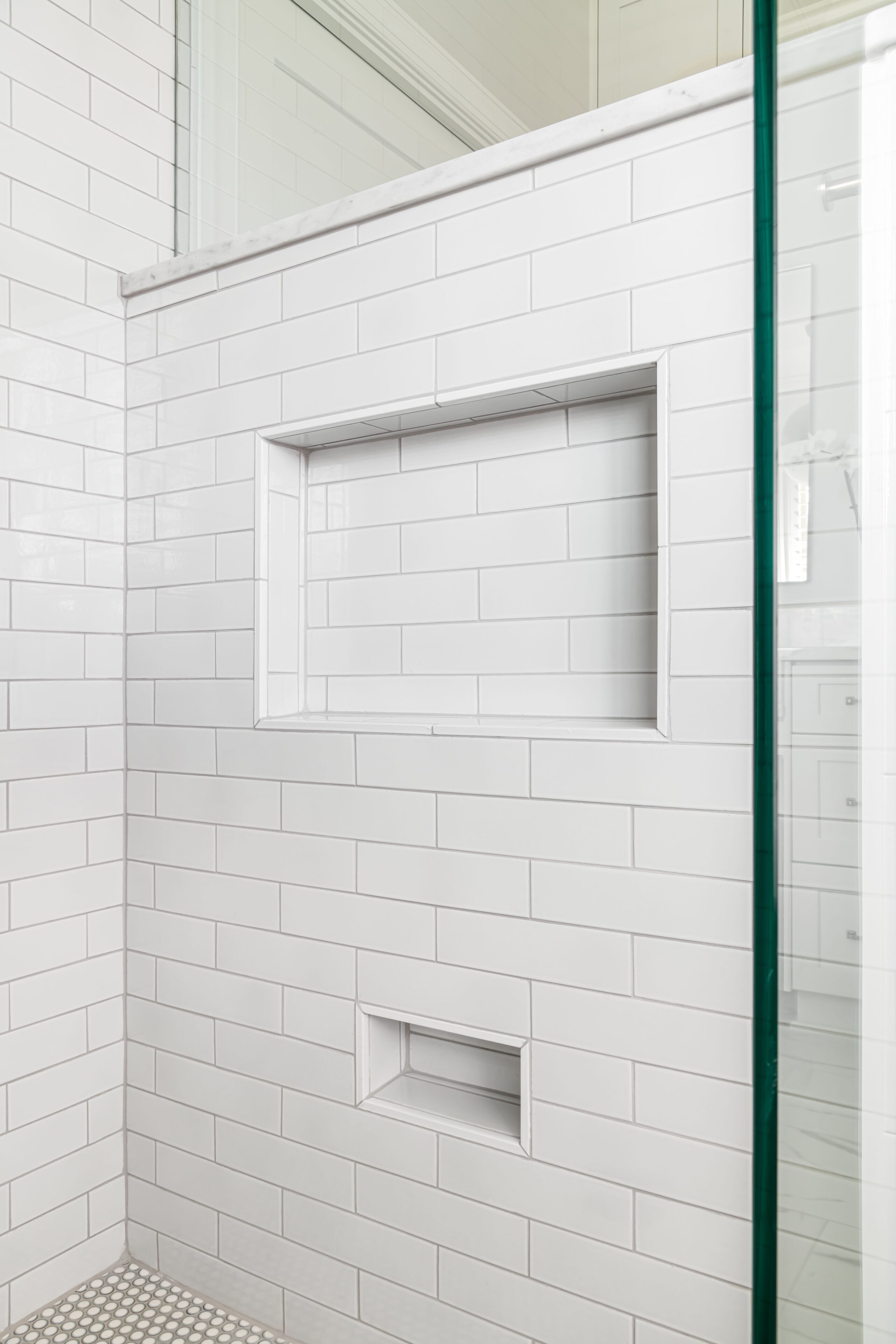 a white tiled shower with a glass shower door