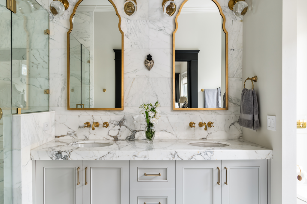 A newly remodeled bathroom with gold fixtures and marble counter
