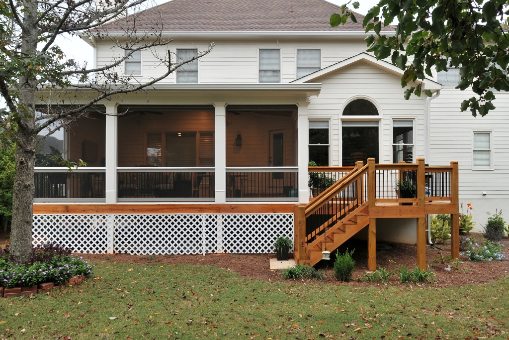 a white house with a screened porch and wooden stairs