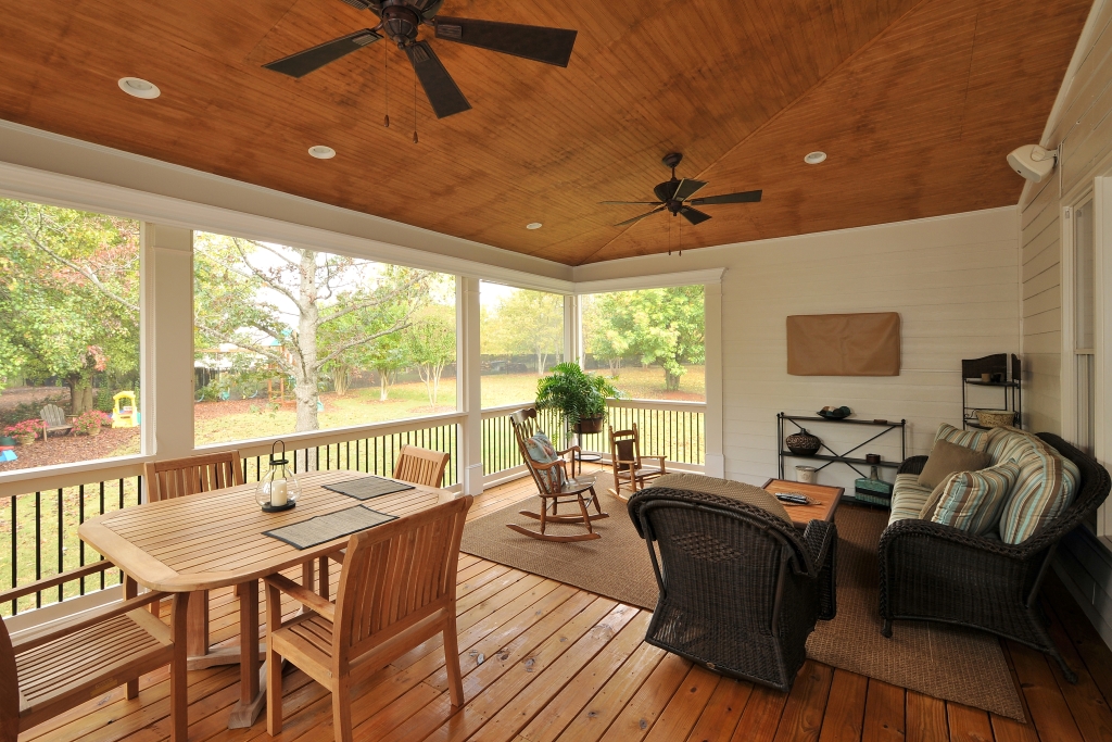 a screened porch with furniture and a ceiling fan