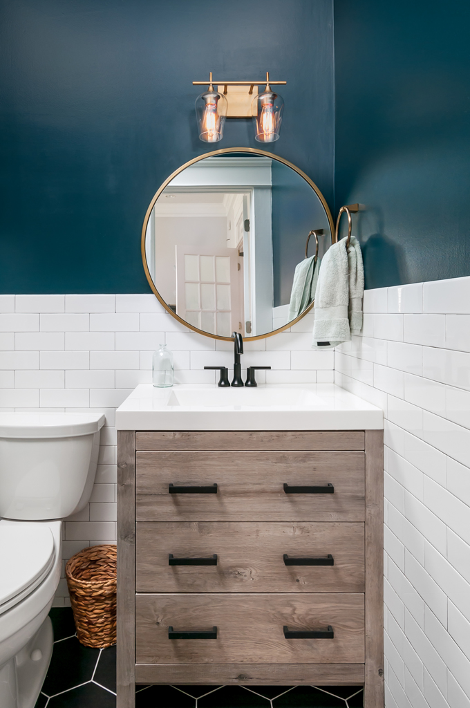 a bathroom with blue walls and white tile with a wooden vanity