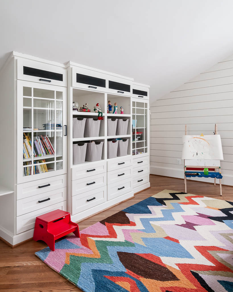 a loft playroom with a vibrant rug, bookshelf and other furniture