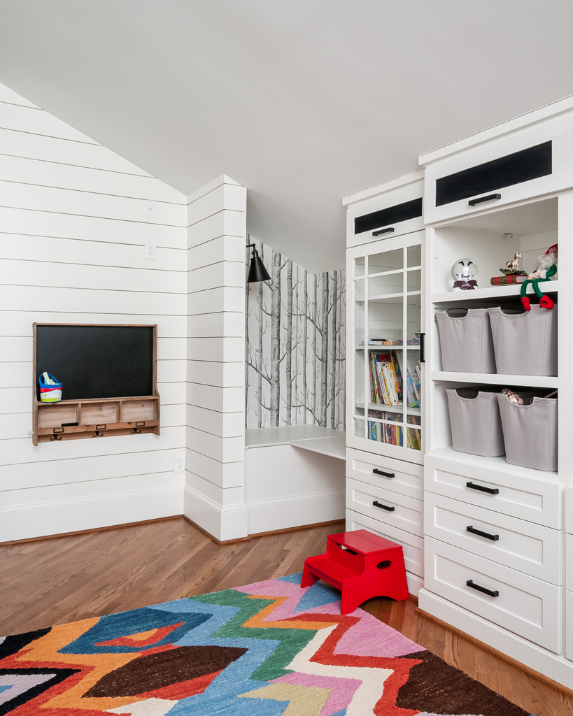 a playroom with white walls and wooden floors and a vibrant rug