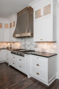 a kitchen with white cabinets, dark marble counter tops, and a gas range stovetop