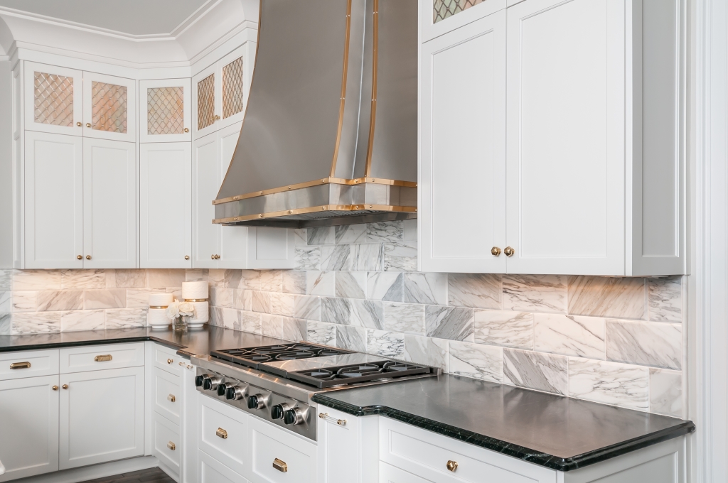 a kitchen with white cabinets and dark marble counter tops with a gas range stove