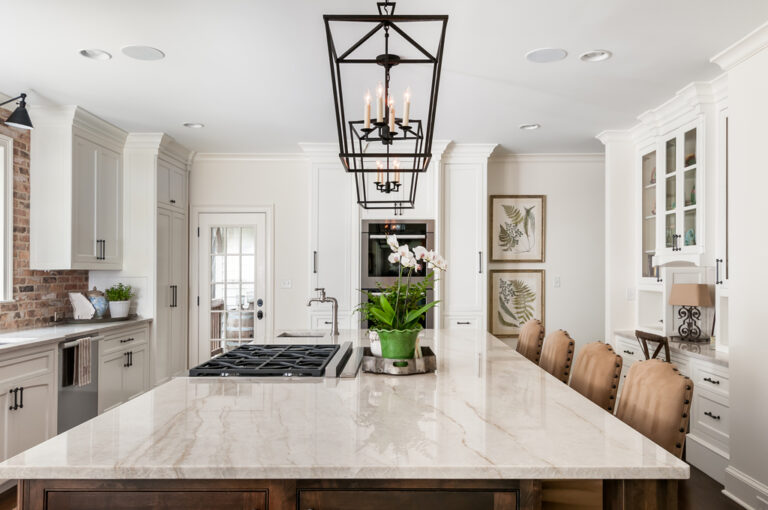 a bright white kitchen with a large center island surrounded by chairs