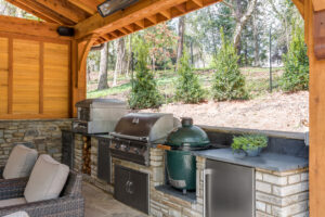 an outdoor kitchen with grill and seating area in a hardscaping remodel project