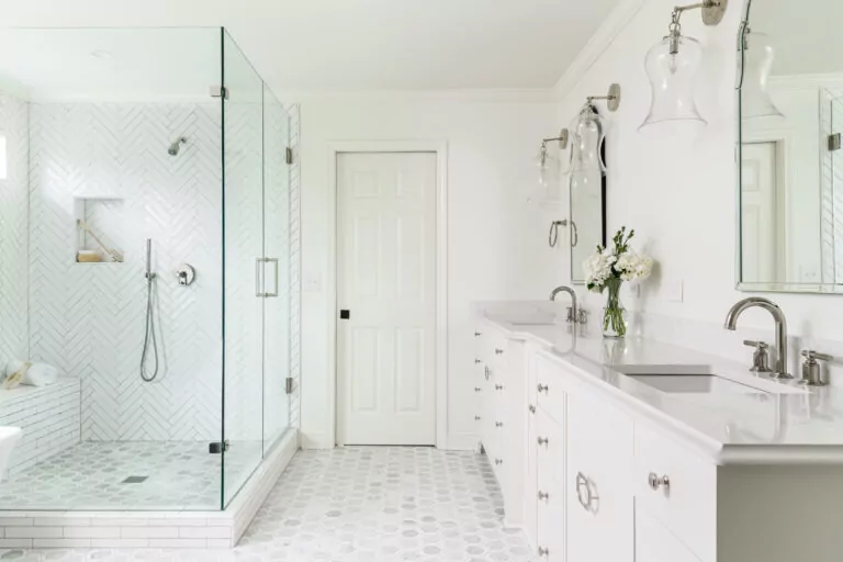 a bright white bathroom with two sinks and a standing shower