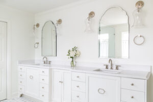 a bright white bathroom with two sinks and mirrors