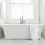 A bathroom renovation with hexagon tiling and a white freestanding tub.