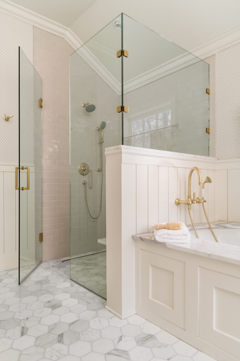 a white bathroom with a glass shower and gold fixtures