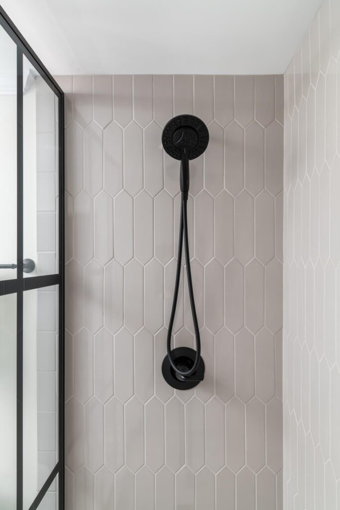a newly remodeled bathroom with a black shower head and tiled walls