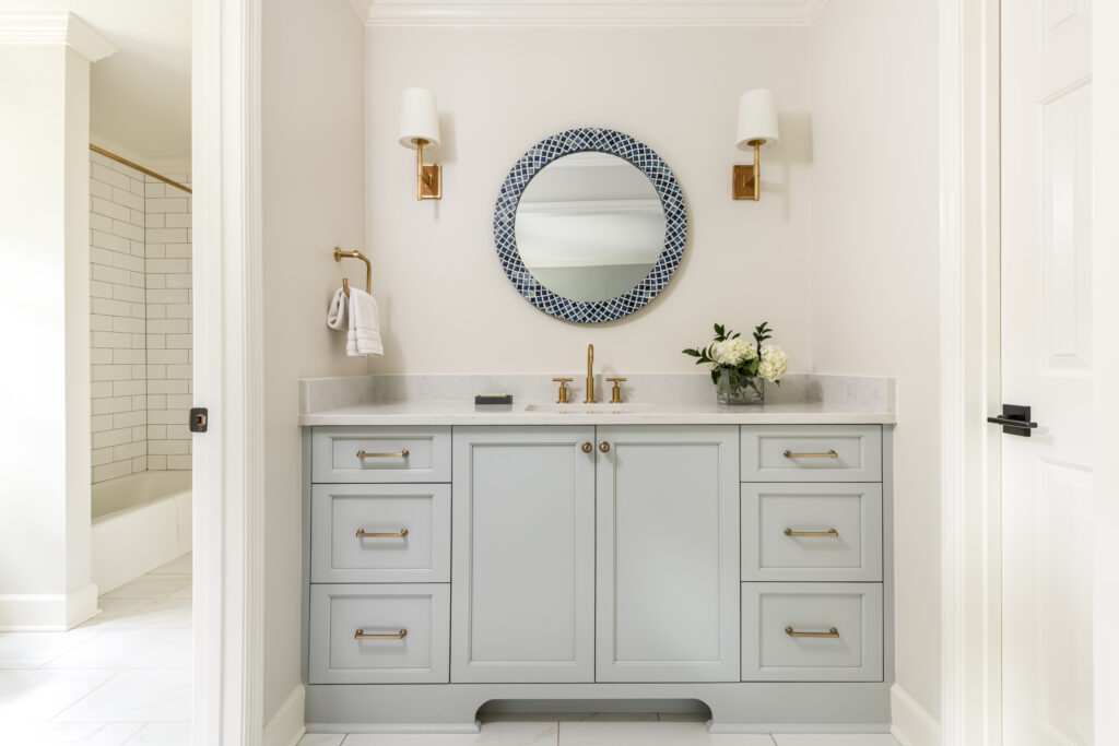 sink & vanity with circle blue-tiled mirror above it