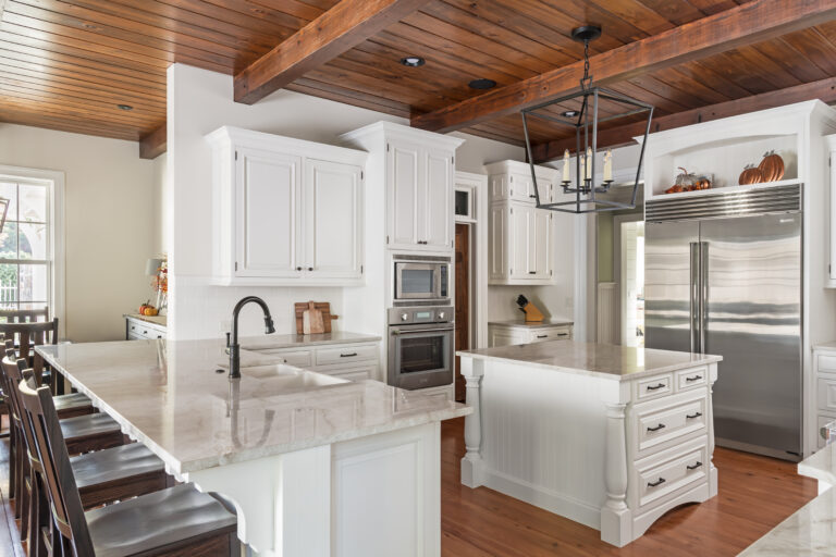 a large kitchen with white cabinets and wooden ceiling