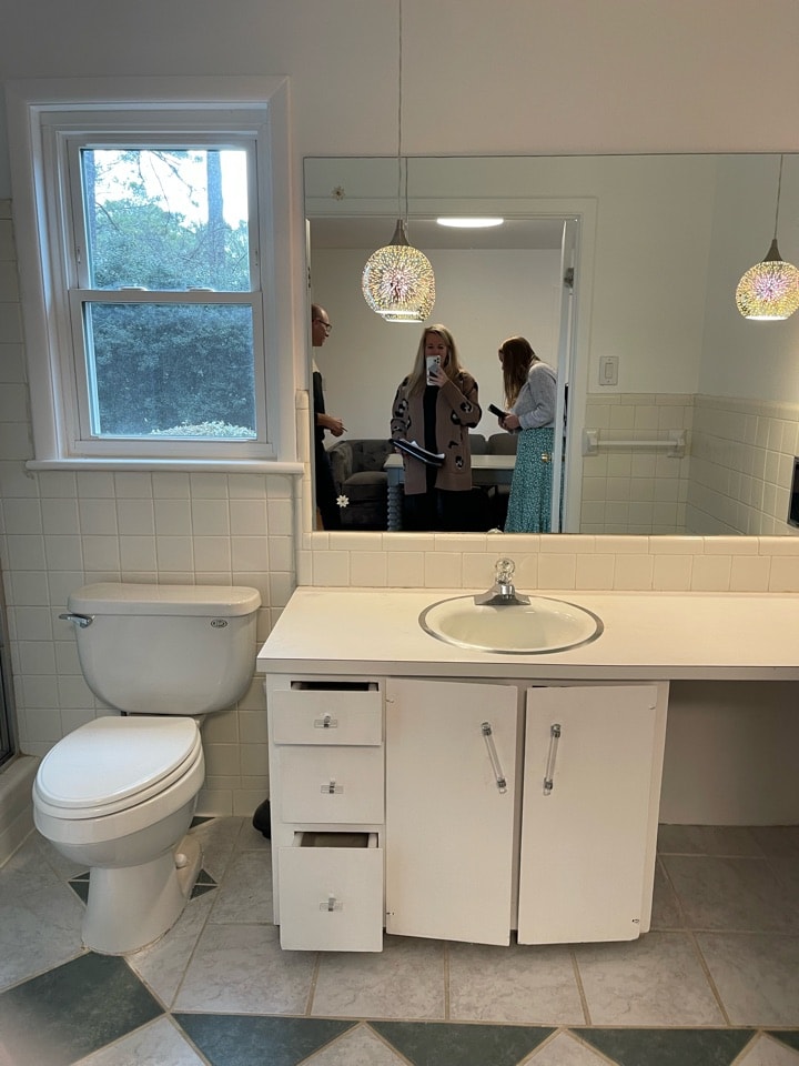 a bathroom with a toilet, sink, and mirror