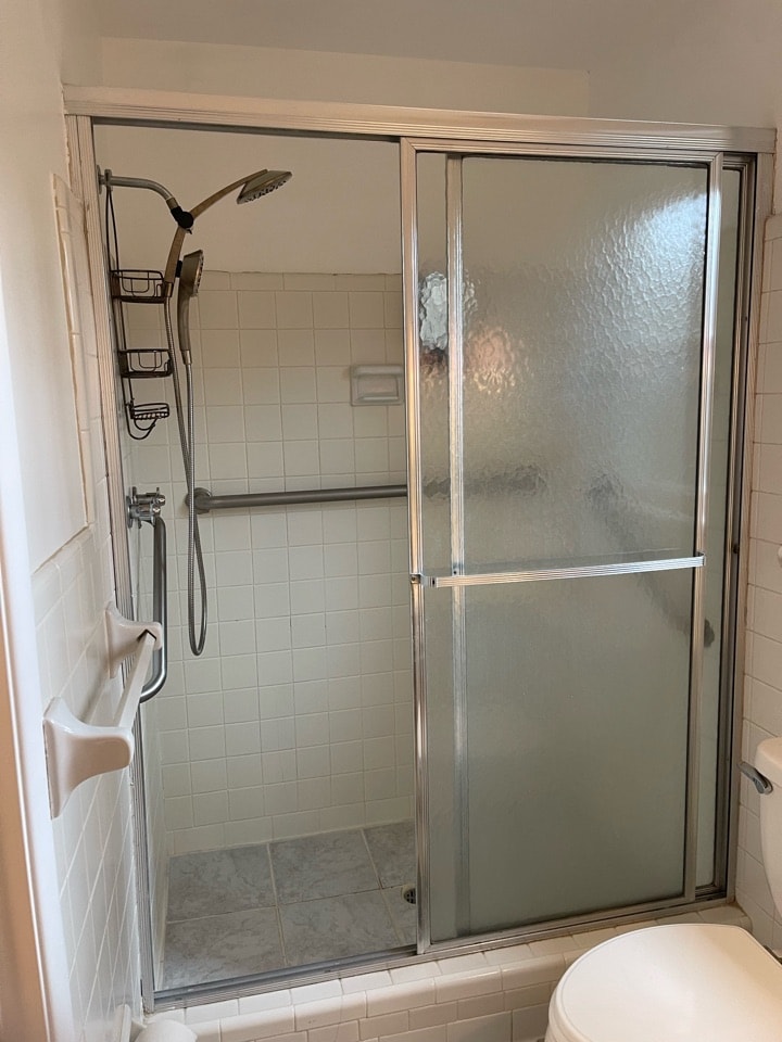 a white toilet sitting next to a walk in shower