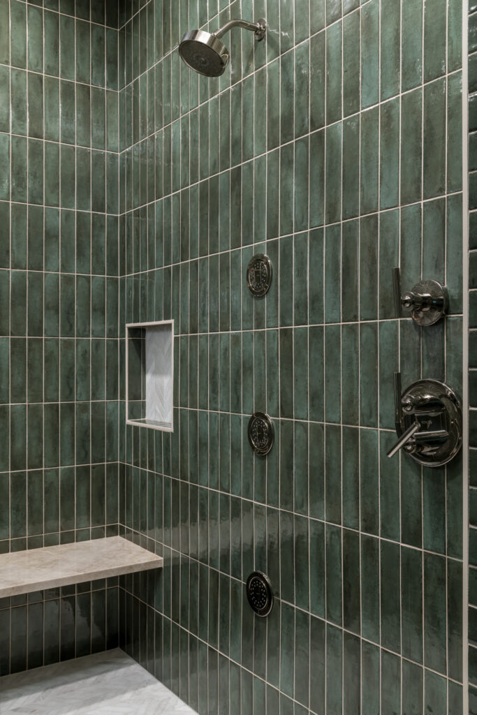 a walk in shower sitting next to a tiled wall