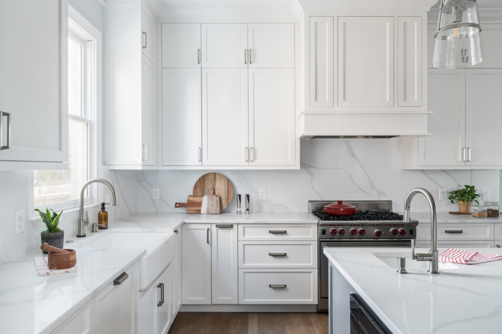 a kitchen with white cabinets and marble counter tops