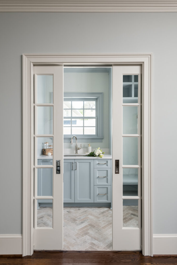 A laundry room-mudroom addition in Buckhead with double pocket French doors and a herringbone floor